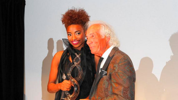 Pryor accepting the 2015 Mario Make Me a Model Competition award, with Mario Tricoci, founder of the event and of Mario Tricoci Hair Salons & Day Spas. 