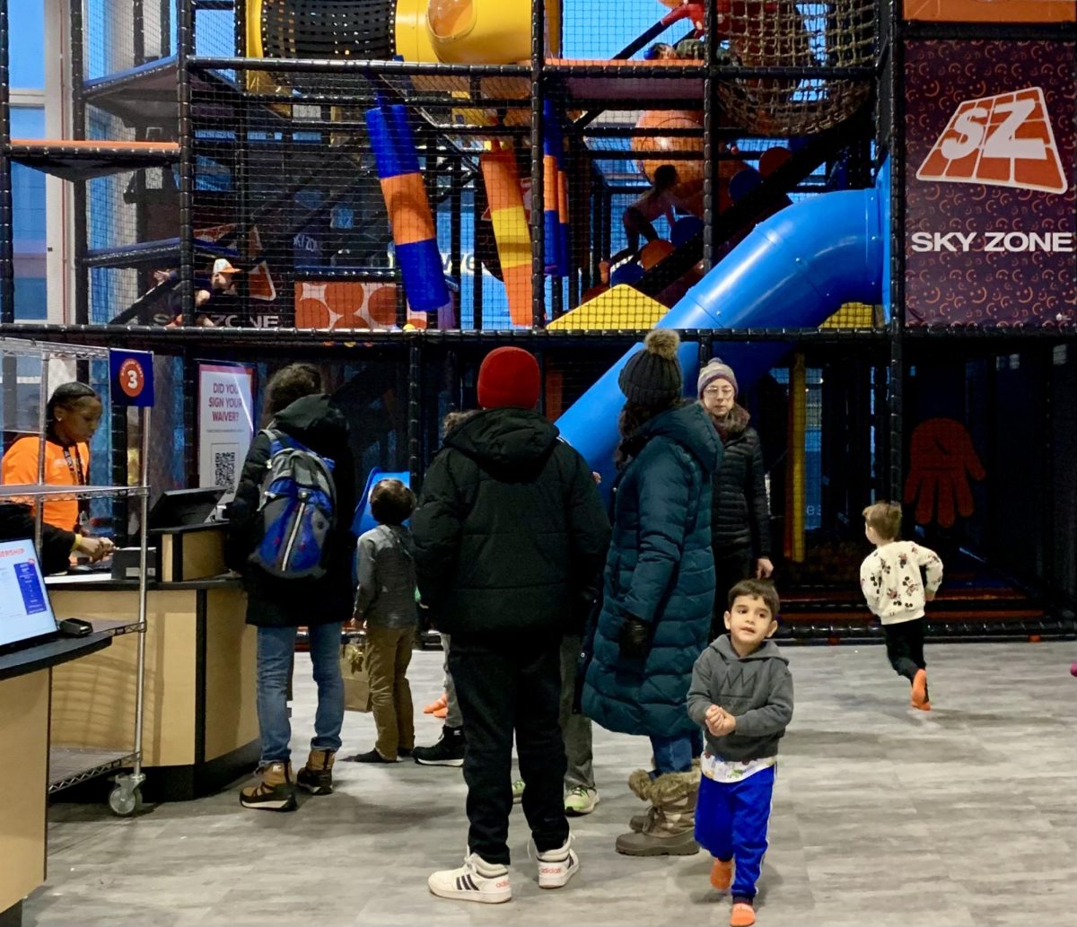 Parents with young children wait to buy tickets, with the multi-leveled tubular playground behind.