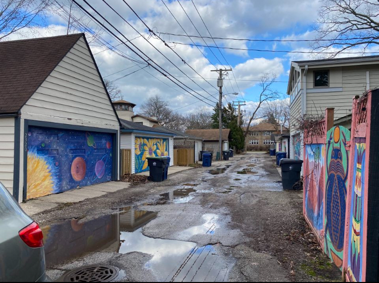 If you take a walk down the alley of the 1400 block of Thayer, Isabella, and Park Street, you will find yourself interacting with some of the most unique and unlikely displays of public art in Evanston – all painted on garage doors in a deserted alley turned-renowned-open-air art gallery.